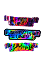 Three identical rectangular stickers with a holographic rainbow sheen and black text reading 'FUND HEALTHCARE NOT WARFARE' on a plain white background.