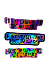 Three identical rectangular stickers with a holographic rainbow sheen and black text reading 'FUND HEALTHCARE NOT WARFARE' on a plain white background.