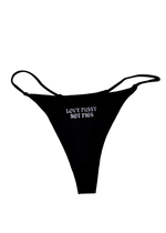 Black string thong with "Love Pussy Not Pigs" printed small in white gothic letters on the front