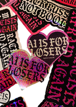 Heart-shaped "AI Is for Losers" glitter stickers in pink and black on a pile of other Cuntry Club stickers