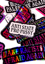 White "Anti State Pro Pussy" sticker with black gothic lettering on a pile of holographic Cuntry Club stickers