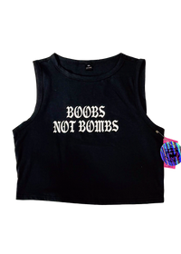 Black cropped tank top laid flat with "Boobs Not Bombs" in white gothic letters and a holographic hangtag