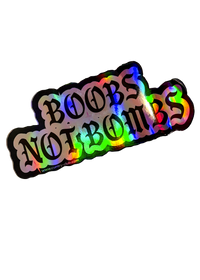 Silver holographic Boobs Not Bombs sticker with black gothic lettering