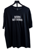 Black t-shirt on a hanger with "Boobs Not Bombs" in white gothic letters on the chest