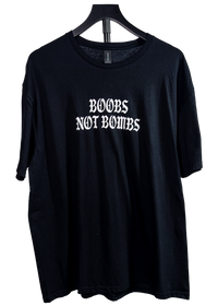 Black t-shirt on a hanger with "Boobs Not Bombs" in white gothic letters on the chest