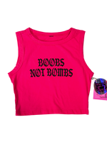 Hot pink cropped tank top laid flat with "Boobs Not Bombs" in black gothic letters and a holographic hangtag