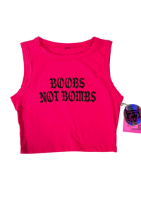Hot pink cropped tank top laid flat with "Boobs Not Bombs" in black gothic letters and a holographic hangtag