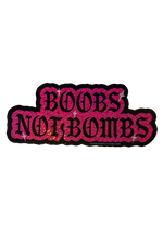 Pink glitter Boobs Not Bombs sticker with black gothic lettering