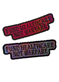 Two Fund Healthcare Not Warfare glitter stickers, one pink and one silver