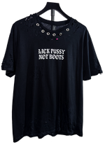 Hand distressed black Lick Pussy Not Boots t-shirt on a hanger with metal grommets around the collar and rips throughout