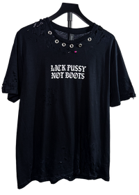 Hand distressed black Lick Pussy Not Boots t-shirt on a hanger with metal grommets around the collar and rips throughout
