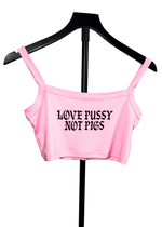 A light pink crop top with the text 'LOVE PUSSY NOT PIGS' printed in black gothic font, displayed on a black hanger against a white background.