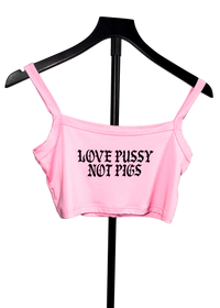 A light pink crop top with the text 'LOVE PUSSY NOT PIGS' printed in black gothic font, displayed on a black hanger against a white background.
