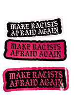 Three Make Racists Afraid Again stickers in black, pink, and black with pink lettering