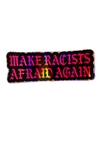A rectangular sticker with a black background and the phrase 'MAKE RACISTS AFRAID AGAIN' in large, colorful gothic-style letters that shift through pink, purple, orange, yellow, and green, set against a plain white background.