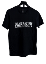 A black short-sleeve crewneck t-shirt hanging on a black hanger against a white background, featuring the text 'MAKE RACISTS AFRAID AGAIN' printed in a white gothic font across the chest.
