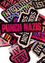 Black Punch Nazis sticker with pink glitter lettering on a pile of stickers