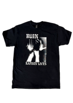 Black t-shirt laid flat with a black and white photo of a figure raising their hands to their face, framed by "Ruin Rapists' Lives" in gothic letters